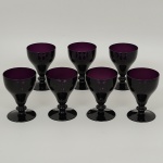 Conjunto de <b>7 copos</b> em cristal na cor berinjela em forma de tulipas com bases circulares. Marca da manufatura William Yeoward no verso. Alt. 14 cm