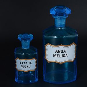 Conjunto de<b> 2 frascos de farmácia </b>franceses em cristal azul turquesa com rótulos do produto de fundo branco e filetados em negro e ouro. Séc. XIX. Alt. 26,5 e 17,5 cm
