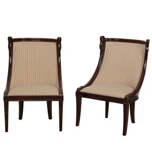 <b>Par de cadeiras para beira de lareira</b>, francesas, no estilo império construída em mogno. Entalhes laterais com cabeças de cisnes. Estofamento em tecido listrado. Alt. 73 cm