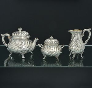 <b>MAISON CHRISTOFLE</b> - Antigo <b>serviço para chá</b> em metal espessurado à prata, decorado em gomos retorcidos e volutas. Pés enrolados. Isoladores do bule de chá em marfim. Constando de bule, leiteira e açucareiro. Alt. do bule de chá 18 cm; Alt. da chaleira 17,5 cm