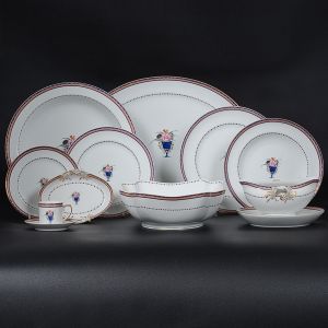 <b>Serviço de jantar </b>em porcelana <b>Vista Alegre</b>, modelo "corbeille", decorado em policromia ao gosto da Companhia da Índias, com uma urna florida e arabescos filetados. Marca da manufatura no verso. Constando de 22 pratos rasos (25,5 cm), 11 pratos fundos, 11 pratos para entrada ou sobremesa, 12 pratos para pão, 10 xícaras par café com pires, 1 molheira navicular com seu "presentoir", 1 pequeno covilhete, 1 travessa oval grande (42 cm), 1 travessa funda circular (31 cm), 1 saladeira. Total de 71 peças.