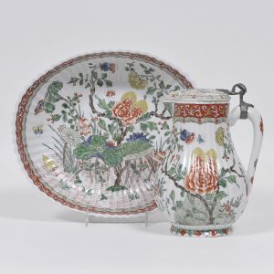 <b>Jarro e bacia</b> em porcelana francesa Sanson profusamente decorada em policromia ao gosto da Família Verde com grandes flores de lótus, peônias, pássaros e insetos. Peças moldadas em gomos com arremate em estanho. Alt. do jarro 23 cm; Med. da bacia 31,5 cm x 27 cm