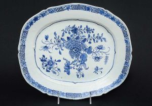 <b>Travessa</b> em porcelana Companhia das Índias decorada em azul índigo "underglaze" sobre fundo branco. Decoração com grande composição florida e borda levemente movimentada. Séc. XVIII. Med. 33,5 x 28,5 cm