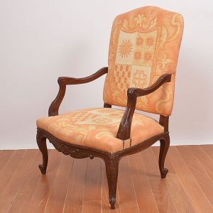 <b>Cadeira de braços </b>francesa com estrutura em madeira de lei. Peça de linhas movimentadas com entalhes fitomorfos, assento e encosto em tecido decorado com brasões. Pés revirados para fora. Séc. XIX. Alt. 107 cm; Larg. 73 cm