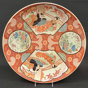Grande <b>medalhão</b> circular japonês, em porcelana, profusamente decorado em policromia com duas reservas com figuras de gueixas e outras floridas. Restante preenchido por arabescos em "rouge de fer". Inscrições no verso. Séc. XIX. Pequeno fio. Diâm. 43 cm