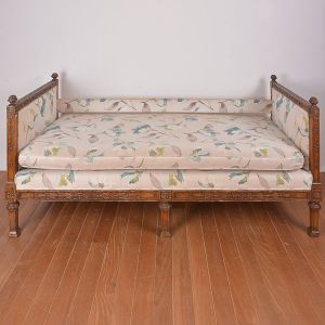 <b>Cama</b> com trave adaptada para sofá, francesa, do início do séc. XIX. Estrutura em madeira entalhada com composições fitomorfas, e parte superior em gregas delimitadas por modelados em forma de pinhas. Estofamento em tecido florido. Med. 96 x 202 x 86 cm
