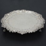 <b>Salva</b> circular em prata portuguesa. Apresenta fundo lavrado com guirlandas e apicoados e  borda em repuxados e cinzelados com flores e folhas de acanto. Triplos pés em garras sobre bolas. Contraste da cidade do Porto e marca de prateiro. Séc. XVIII. Diâm. 23 cm. Peso 400 gramas.