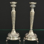 <b>Par de castiçais</b> em prata 833 ml, decorados com angras e acantos. Triplos pés em garras. Apresentam enchimento. Marca de prateiro na base. Alt. 28 cm
