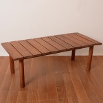 <b>TENREIRO, JOAQUIM </b><br>(1906-1992)<Br><b>Mesa retangular de centro</b> em madeira nobre com tampo ripado e pernas cilíndricas retas. Apresenta selo do fabricante. Med. 38 x 110 x 50 cm