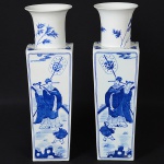 Par de antigos <b>vasos</b> em porcelana chinesa, apresentam feitio retangular com gargalos circulares de bocais levemente abertos. Decoração com figuras de nobres, flores e pássaros em azul índigo underglaze sobre fundo branco. Alt. 51,5 cm