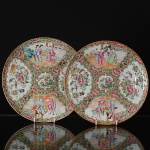 <b>Par de pratos</b> circulares em porcelana Mandarim, profusamente decorados em policromia com personagens em cenas do cotidiano, flores, pássaros e borboletas. Séc. XIX. Diâm. 25 cm