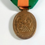 IMPÉRIO DO BRASIL - GUERRA DO PARAGUAI - MEDALHA DE RECOMPENSA À BRAVURA MILITAR COM FITA. Criada por D. Pedro II por Dec 4131 de 28 mar 1868, destinada aos que dela se tornaram dignos pela sua bravura em qualquer ação de guerra durante a Campanha do Paraguai. Era oval, de bronze e usada do lado esquerdo do peito, pendente de fita com três listras, a central escarlate e as extremas verdes. Ela possuía tantos passadores quantos fossem as concessões por ações em que praticou ato de bravura. As ações figuravam pela data, ou pelo nome histórico que tomou a ação. O anverso: Um conjunto de troféus circundado pela legenda – Exército em operações contra o Governo do Paraguai. Reverso: Inscrição central Recompensa à Bravura Militar, circundado pela inscrição Decreto de 28 de março de 1868. Ela foi estendida a Marinha por Dec 4143 de 5 abr 1868.