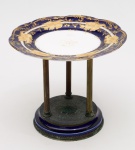 Fruteira em porcelana europeia, possivelmente francesa, na coe azul cobalto e ouro. Estrutura da base em bronze. Diâmetro: 23 cm. Altura: 20 cm.