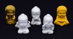 Conjunto de cinco Budas em materiais diversos, sendo três em porcelana branca e dois coloridos em material sintético: Altura: 9 cm (cada).