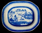 CIA DAS INDIAS CANTÃO BELA TRAVESSA OVAL EM PORCELANA UNDERGLAZE DO PERÍODO QIANLONG (1736-1795). BORDA COM BARRADOS EM AZUL. RESERVA COM CENAS LACUSTRES, COM BARCOS, PONTES E PAGODES. CHINA, SEC. XVIII. 35 CM DE COMPRIMENTO. NOTA: NOTA: Jean Hugues van Linschooten voltou para a Holanda, seu país natal, em 1593. Ele chegava de Goa, então a capital das colônias portuguesas do Oriente, onde ocupara a função de secretário do arcebispado. O retorno desse modesto funcionário a Amsterdã poderia ter passado despercebido a seus contemporâneos caso o viajante, ainda maravilhado por tudo o que vira, não tivesse redigido uma obra intitulada Itinerário, viagem ou navegação às Índias Orientais. Era uma verdadeira mina de informações sobre as fabulosas riquezas desses lugares longínquos, acrescida de uma lista de plantas e animais extraordinários que lá existiam e complementada por mapas, desenhos e anotações, de maneira a permitir uma navegação bastante segura a quem se aventurasse pela rota. O autor incitava seus compatriotas a organizar expedições para o Leste, sem esquecer Java, "uma ilha ainda não frequentada pelos portugueses, onde abundam diamantes, incenso e especiarias". Nessa época, Portugal e Espanha captavam em seus portos de Lisboa e Cádiz a maior parte das riquezas vindas do Oriente. Franceses, ingleses e holandeses se deslocavam até essas bases de comércio para adquirir as mercadorias que depois distribuíam em seus respectivos países. Um Capítulo especial de Linschooten se refere a profusão das porcelanas e a qualidade com que se apresentavam. Estas porcelanas nos séculos seguintes viriam a cair em cheio no gosto de nobres e burgueses europeus. Mas a que custo! A missão de um navio da Companhia das Índias durava muitos meses. Às vezes a embarcação só voltava ao porto de origem dois anos depois da partida, pois, além de as negociações comerciais no Oriente serem muito demoradas, era preciso esperar por ventos favoráveis para tomar o caminho de volta. Desde os portos do noroeste da Europa até Cantão, situado na costa chinesa, na embocadura do rio das Pérolas, um grande centro comercial, contam-se de 15 a 16 mil milhas. A partida da Europa dependia da data das monções. Levava-se quatro meses para atingir o cabo da Boa Esperança e, para passar por esse temível promontório na época propícia, era necessário sair da Europa no inverno, entre dezembro e março. A chegada a Cantão, ou mais exatamente a Wampu ou Huang Fu, acontecia, na melhor das hipóteses, no final do verão ou no início do outono, geralmente em setembro. A monção continental que se inicia em outubro levava os navios na direção do cabo. Além das circunstâncias imprevisíveis que sempre acompanham as expedições no mar, esses navios mercantes não dispunham de cartas marítimas elementares. Os portugueses guardavam em segredo as anotações feitas por seus capitães. Chegariam ao ponto de falsificar algumas delas, assim como fariam os holandeses mais tarde, deixando-as "escapulir" para as nações concorrentes, na intenção de provocar desastres ou naufrágios, dos quais tiravam, evidentemente, total benefício. Portugal estabeleceu com Cantão um monopólio de comércio que se revelou por mais de um século como uma lucrativa empreita. Por isso era frequente o uso de porcelana característica do Cantão nos países membros do império ultramarino português