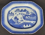 CIA DAS INDIAS CANTÃO BELA TRAVESSA  EM PORCELANA UNDERGLAZE DO PERÍODO QIANLONG (1736-1795). BORDA COM BARRADOS EM AZUL. RESERVA COM CENAS LACUSTRES, COM BARCOS, PONTES E PAGODES. A BASE TEM A DESEJÁVEL FINALIZAÇÃO UNGLAZED (SEM COBERTURA DO ESMALTE) QUE MOSTRA A PASTA RUGOSA DA PORCELANA COM A COR NATURAL DA ARGILA (TÍPICA DA BOA PRODUÇÃO DO PERÍODO QIANLONG).CHINA, SEC. XVIII. 39 CM DE COMPRIMENTO.