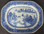 CIA DAS INDIAS  - REINADO QIANLONG - BELA TRAVESSA  EM PORCELANA UNDERGLAZE DO PERÍODO QIANLONG (1736-1795). BORDA COM BARRADOS EM AZUL. RESERVA COM CENAS LACUSTRES, COM BARCOS, PONTES E PAGODES. A BASE TEM A DESEJÁVEL FINALIZAÇÃO UNGLAZED (SEM COBERTURA DO ESMALTE) QUE MOSTRA A PASTA RUGOSA DA PORCELANA COM A COR NATURAL DA ARGILA (TÍPICA DA BOA PRODUÇÃO DO PERÍODO QIANLONG).CHINA, SEC. XVIII.  32 CM DE COMPRIMENTO.