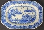 CIA DAS INDIAS  - REINADO QIANLONG - BELA TRAVESSA  EM PORCELANA UNDERGLAZE DO PERÍODO QIANLONG (1736-1795). BORDA COM BARRADOS EM AZUL. RESERVA COM CENAS LACUSTRES, COM BARCOS, PONTES E PAGODES. A BASE TEM A DESEJÁVEL FINALIZAÇÃO UNGLAZED (SEM COBERTURA DO ESMALTE) QUE MOSTRA A PASTA RUGOSA DA PORCELANA COM A COR NATURAL DA ARGILA (TÍPICA DA BOA PRODUÇÃO DO PERÍODO QIANLONG).CHINA, SEC. XVIII.  27  CM DE COMPRIMENTO.