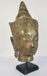 BHUDA AYUTTHAVA -  LINDA CABEÇA EM BRONZE APRESENTANDO CABEÇA DE BHUDA SEGUNDO O ESTILO AVUTTAHAVA, SEGUNDO REINO DO SIÃO. TAILANDIA, SEC. XIX. 39 CM DE ALTURA.NOTA: Durante os séculos XIV a XVI, o reino de Ayutthaya, na Tailândia, tornou-se uma das forças mais poderosas do Sudeste Asiático continental. Continuando a trajetória artística estabelecida no Sukhothai, o governo Theravada patrocinou a produção de imagens de Buda moldadas em um novo estilo distinto. Imagens de Buda em trajes reais, como o presente exemplo onde ele é coroado e enfeitado com joias, tornaram-se cada vez mais populares. Os rostos do período Ayutthaya exibem um contorno curvilíneo com a linha do cabelo estendendo-se em direção à linha sinuosa da testa, acentuada por orelhas alongadas alargadas nas pontas superior e inferior. Os olhos, estendendo-se uniformemente por toda a largura do rosto, estão três quartos fechados para dotar a figura de uma sensação de serenidade que é ao mesmo tempo dirigida para dentro e também envolvida com o mundo. O Reino de Ayutthaya , o segundo Reino Siamês, existiu do século XIV ao século XVIII e é conhecido pelos seus colossais mosteiros e prang (torres relicárias). O nome  Ayutthaya  foi derivado da antiga cidade indiana  Ayodhya . Tornou-se uma das maiores e mais cosmopolitas áreas urbanas do mundo e serviu como centro para a diplomacia e o comércio comercial. Os comerciantes estrangeiros sempre foram bem-vindos no reino de Ayutthaya , tornando-o um centro de comércio com chineses, vietnamitas, indianos, persas e japoneses. Durante o século XVI, o Reino de Ayutthaya tornou-se uma das maiores e mais ricas cidades do Oriente, proporcionando abrigo aos comerciantes portugueses, holandeses, espanhóis e franceses fora dos muros da capital. O Reino de Ayutthaya estava localizado em uma ilha cercada por três rios, ligados ao mar, o que o tornava estrategicamente central para o comércio exterior e a diplomacia. Até os embaixadores da França durante o reinado do rei Luís XIV compararam o reino de Ayutthaya a Paris em termos de riqueza e tamanho. Afirmou-se que a corte do rei Narai tinha fortes ligações com o rei Luís XIV para aumentar a potência comercial. urante a época do Reino de Ayutthaya , os reis eram monarcas semi-religiosos que seguiam várias ideologias tanto do hinduísmo quanto do budismo. A religião predominante no Reino de Ayutthaya era o Budismo Theravada , mas segundo a tradição hindu, os reis eram vistos como avatares do Senhor Vishnu , nascidos para proteger o povo dos demônios. De acordo com o budismo, o rei era conhecido como um governante justo cujo objetivo era satisfazer o bem-estar do povo seguindo rigorosamente os ensinamentos do Senhor Buda .O Reino de Ayutthaya foi inicialmente governado pela 1ª Dinastia Uthong , que durou de 1350-1370. O primeiro rei de Ayutthaya foi Somdet Phra Chao Uthong , também conhecido como Somdet Phra Ramathibodi I. Ramathibodi I garantiu sua posição como rei por meio de casamentos e alianças políticas. Após sua morte, seguiu-se um conflito sobre a sucessão, que acabou levando seu filho Somdet Phra Ramesuan a assumir o poder, mas ele foi posteriormente sequestrado, causando uma guerra civil.Depois de derrubar a dinastia Uthong e tomar o trono do Reino de Ayutthaya do Rei Ramesuan, o Senhor de Suphanburi tornou-se o terceiro rei de Ayutthaya, iniciando a Dinastia Suphannaphum em 1370. Somdet Phra Borommarachathirat I, também conhecido como Khun Luang Pha Ngua, reinou sobre o reino por 18 anos e expandiu-o para o norte. Ele derrotou várias potências do norte de Phitsanuloke e subjugou a rebelião no Reino de Sucotai . No entanto, seu exército foi derrotado ao invadir Chiang Mai. O segundo rei da Dinastia Suphannaphum e o quarto rei do Reino de Ayutthaya foi Somdet Phrachao Thonglan , cujo reinado durou apenas uma semana antes de ser executado. Depois de ser deposto pelo rei Somdet Phra Borommarachathirat I, o rei Ramesuan, com apoio e poder suficientes, assumiu o trono novamente após executar Thonglan, de 17 anos. Durante seu segundo reinado, o rei Ramesuan capturou Chiang Mai, capital de Lan Na. Nos últimos 400 anos, muitos reis governaram uma das maiores e mais belas cidades do mundo naquela época. Aproximadamente 33 reis de diferentes dinastias governaram este reino e contribuíram para a sua beleza até à sua destruição total. No período de 417 anos, o reino foi adornado com belos mosteiros, pagodes, estátuas de Buda , templos  e palácios budistas .A Dinastia Prasat Thong teve uma influência significativa na criação de belas estruturas neste antigo reino. O primeiro rei da dinastia Prasat Thong, o rei Prasat Thong , construiu Wat Chaiwatthanaram , um dos magníficos templos budistas que fica na cidade do Reino de Ayutthaya . O nome do templo significa " O Templo do Longo Reinado e da Era Gloriosa ". Wat Chaiwatthanaram foi construído no estilo arquitetônico Khmer e apresenta um prang de 35 metros de altura com outros quatro prangs semelhantes. Toda a estrutura assenta numa plataforma rectangular e está rodeada por oito capelas em forma de chedi. Estas capelas são únicas, com diversas pinturas nas paredes interiores e 12 relevos representando cenas da vida do Senhor Buda , que devem ser lidos no sentido horário. Durante a mesma dinastia, o rei Narai, o Grande, também conhecido como Ramathibodi III, construiu Wat Kudi Duo, um templo budista que mais tarde foi restaurado pelo rei Thai Sa da dinastia Ban Phlu Luang. Este templo foi construído no estilo tardio de Ayutthaya e apresenta o Ubosot (sala de ordenação), o Viharn (salão de imagens), o princípio em forma de sino Chedi no estilo do Sri Lanka e muito mais.O primeiro rei que iniciou o Reino de Ayutthaya , o rei U-thong, também construiu Wat Yai Chai Mongkhon, um templo budista construído para acomodar monges. Outros importantes templos budistas construídos durante a existência do Reino de Ayutthaya incluem Wat Ratchburana, Wat Phanan Choeng, Wat Phra Si Sanphet e o Templo Wat Tuek, que ainda está ativo hoje. O Templo Wat Tuek consiste em duas salas de sermões, e o Ubosot no templo abriga um grande número de imagens de Buda em várias poses. Vários santuários modernos servem como monumentos a Buda, monges e algumas divindades hindus modernas .Wat Ratchburana foi fundado pelo Rei Borommarachathirat II da Dinastia Suphannaphum. O prang principal do templo é um dos melhores da cidade e contém um raro exemplo do início do período de Ayutthaya. Também abriga inúmeras imagens de Buda , artefatos de ouro e o Museu Chao Sam Phraya, apresentando influências dos estilos Khmer e Sukhothai.A arquitetura monástica de Wat Phra Si Sanphet foi alinhada num eixo leste-oeste, com o núcleo do templo apresentando três chedis idênticos construídos sobre uma plataforma retangular. Esses três chedis foram construídos no estilo Sukhothai, influenciado pela Srivijayan Stupa. Eles foram construídos por três reis: Rei Ramathibodi II, Rei Borommaracha III e Rei Boromracha IV. Apesar da invasão do exército birmanês, muitas estátuas e templos de Buda foram destruídos, mas várias estruturas ainda existem, como Wat Mahathat, onde você pode ver uma cabeça de Buda coberta de árvores.