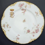 BARÃO DE POTENGI (INACIO DE AMERICA PINHEIRO, 1830-1892) - PRATO EM PORCELANA FRANCESA DE LIMOGES, MANUFATURA "HAVILAND & Cº", SÉC XIX. ESMALTADO COM RAMOS DE ROSA EM POLICROMIA. BORDA MONOGRAMA " BP " EM DOURADO E ROSA SOB COROA DE BARÃO. BORDA ONDULADA COM FRISO DOURADO. REPRODUZIDO NO LIVRO "LOUÇA DA ARISTOCRACIA NO BRASIL" POR JENNY DREYFUS NA PAG. 309. EXEMPLAR DESSE SERVIÇO COMPÕE TAMBÉM O ACERVO DO MUSEU IMPERIAL DE PETRÓPOLIS. 24 CM DE DIAMETRO. NOTA: IGNÁCIO JOSÉ DA AMÉRICA PINHEIRO, PRIMEIRO E ÚNICOBARÃO DE POTENGI (VALENÇA  IO DE JANEIRO,19 DE OUTUBRO DE 1892) FOI UM NOBRE BRASILEIRO. FILHO DE JOSÉ PINHEIRO DE SOUSA E DE ISABEL MARIA DA VISITAÇÃO, QUE ERA FILHA DE INÁCIO DE SOUSA WERNEK. CASOU-SE COM ANA PEREGRINA PINHEIRO WERNECK (1837 - 13 DE MARÇO DE 1925), E TORNOU-SE BARONESA DE POTENGI. AGRACIADO COM O TÍTULO DE BARÃO, POR DECRETO IMPERIAL DE17 DE JUNHO DE 1882.ERA IRMÃO DO VISCONDE DE IPIABAS, PEREGRINO JOSÉ DE AMÉRICA (OU DAMERICA) PINHEIRO (1811-1882) QUE FOI SENHOR DA FAMOSA FAZENDA ORIENTE EM VASSOURAS. A FAMÍLIA PINHEIRO TORNOU-SE UM  DOS MAIS IMPORTANTES CLÃNS CAFEEIROS DO BRASIL. UMA DAS FILHAS DO VISCONDE DE IPIABAS, DONA ANA PEREGRINA, PINHEIRO WERNECK VEIO A CASAR-SE COM O BARÃO DE POTENGI, IRMÃO DO VISCONDE IPIABAS, TORNANDO-SE PORTANTO TIO DE SUA ESPOSA E CUNHADO DE SEU IRMÃO. O VISCONDE DE IPIABAS E SEU IRMÃO O BARÃO DE POTENGY ERAM MEMBROS DA ANTIGA ARISTOCRACIA RURAL FLUMINENSE, ERAM UM DOS MAIORES PRODUTORES DE CAFÉ EM VALENÇA, RIO DE JANEIRO. PEREGRINO FOI COMENDADOR E CORONEL DA GUARDA NACIONAL, SENDO TAMBÉM AGRACIADO COM AS INSÍGNIAS DAS ORDENS DE CRISTO E DA ROSA, ALÉM DE SER MOÇO FIDALGO COM EXERCÍCIO NA CASA IMPERIAL. FOI PROVEDOR DA SANTA CASA DE MISERICÓRDIA DE VALENÇA E MEMBRO DO INSTITUTO HISTÓRICO E GEOGRÁFICO BRASILEIRO, ALÉM DE CONTRIBUIR COM ELEVADA SOMA DE DINHEIRO PARA A CRIAÇÃO DO CORPO DO EXÉRCITO DO BRASIL QUE LUTOU NA GUERRA DO PARAGUAI. EXTREMAMENTE RELIGIOSO, COLABOROU PARA A RESTAURAÇÃO, E MESMO CONCLUSÃO, DE VÁRIAS IGREJAS LOCALIZADAS NA ÁREA DE VALENÇA. CASOU-SE NO DIA 4 DE FEVEREIRO DE 1841 COM SUA PRIMA-IRMÃ ANA ISABEL WERNECK, COM QUEM TEVE 15 FILHOS. PELA SUA INICIATIVA EM CONSTRUIR ESCOLAS, HOSPITAIS E EM LIBERTAR A MAIORIA DE SEUS ESCRAVOS E TORNA-LOS TRABALHADORES ASSALARIADOS, RECEBEU DO IMPERADOR INÚMERAS CONDECORAÇÕES, SENDO CAVALEIRO DA IMPERIAL ORDEM DA ROSA, DA IMPERIAL ORDEM DE CRISTO E TÍTULOS DE BARÃO E VISCONDE DE IPIABAS. FALECIDO EM 1883 DEIXOU PARA SEUS DESCENTES 38 ESCRAVOS, E MAIS DE 100 CONTOS DE RÉIS. A ABOLIÇÃO DA ESCRAVIDÃO TROUXE GRANDES PREJUÍZOS FINANCEIROS A FAZENDA DA FAMÍLIA, QUE ERA ADMINISTRADA POR SUA VIÚVA, DONA ANA WERNECK QUE ACUMULOU MAIS DE 150 CONTOS DE RÉIS ANTES DE SUA MORTE EM 1892. NA VIRADA DO SÉCULO XX, A FORTUNA DA ANTIGA FAMÍLIA CAFEEIRA JÁ HAVIA EVAPORADO ENTRE OS DESCENDENTES. (VIDE NOS CRÉDITOS EXTRAS DESSE LOTE FOTOGRAFIA DO RETRATO DO VISCONDE DE IPIABAS)