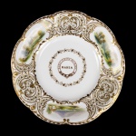 MARIA JOANNA MACHADO  LINDO PRATO EM PORCELANA DA IMPORTANTE MANUFATURA INGLESA DE DAVENPORT. FEITIO RECORTADO E LUXUOSAMENTE REMATADO EM OURO.  DECORADO COM PINTURAS MANUAIS REPRESENTANDO CENAS LACUSTRES E RUÍNAS ARQUITETÔNICAS. NA CALDEIRA ENTRE GUIRLANDA DE FOLHAS EM OURO, RESERVA COM CIRCULO CONTENDO AS INSCRIÇÕES MARIA JOANNA MACHADO E AO CENTOR EM DESTAQUE BAHIA. GUARNECEU A RESIDÊNCIA DA ARISTOCRATA QUE ERA NETA MARECHAL JEAN BAPTISTE JOURDAN, OFICIAL DE CONFIANÇA DO IMPERADOR NAPOLEÃO BONAPARTE QUE SE ENCONTRA SEPULTADO AO LADO DO IMPERADOR NO PALÁCIO NACIONAL LES INVALIDES. FOI CASADA COM O COMENDADOR FRANCISCO XAVIER MACHADO VIVIAM EM UM SUNTUOSO SOLAR QUE DESDE 1877  ABRIGA O ASILO DA MENDICIDADE DOM PEDRO II. EXEMPLAR DESSE SERVIÇO ESTÁ REPRODUZIDO NA PÁGINA 77 DO LIVRO LOUÇA HISTÓRICA DO MUSEU DE ARTE DA BAHIA. MEADOS DO SEC. XIX. 23 CM DE DIAMETRO