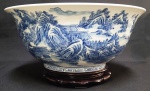 LINDO BOWL EM PORCELANA DECORADA EM AZUL COM EXUBERANTE PAISAGEM COM VEGETAÇÃO, PERSONAGENS E CENA LACUSTRE COM BARCO. LINDA BASE EM MADEIRA ENTALHADA. SELO COM MARCAS DO PERIODO YONGZHENG, CHINA, SEC. XX. 39 CM DE DIAMETRO