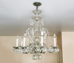 Antigo lustre europeu de cristal, adornado por grandes pingentes facetados, 8 braços ligados por correntes de medalhas lapidadas, 1 bobeche quebrada. Medida 110 x 80 cm.