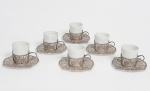 Colecionismo - conjunto de 6 xícaras de café em porcelana, suporte e pires de prata brasileira, contrastada 833 ml, e decorados com Brasão de Armas da Republica Federativa do Brasil e de Portugal, pires adornados por cinzelados formando coroas e por moedas de 1.000 Réis - Petrus II, do período de 1850 a 1866, medida do pires 10,5 cm.. Peso total da prata 514 g.