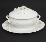 LIMOGES França - Belíssima sopeira com presentoir em porcelana branca adornada com flores em relevos, Apresenta pequenas perdas e pequenos restauros nas flores. Medindo 35 x 50 cm.