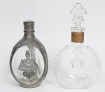 Duas garrafas de coleção: Baccarat Remy Martin Louis XIII, com trincado circular nos dois lados. E garrafa  Dimple de estanho 'Royal Holland Pewter Daalderop'. Medindo 28 x 17 cm. e 22 x 13 cm