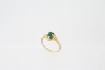 Delicado anel para criança em ouro 18 K com uma pedra central no tom verde possivelmente uma esmeralda - med. 1x1 cm - aro 7 - peso bruto aproximado - 1,8 gr (pedra com trincado interno)