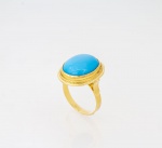 Anel em ouro 750 ml contrastado com cabochom em pedra azul possivelmente turquesa - med. 1,7x2 cm - aro 17 - peso bruto aproximado - 5,5 gr