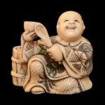 Netsuke esculpido em marfim com realces policromados, representando homem sentado tomando sopa. Assinado sob a base. 3.5 x 3.5 x 2 cm.