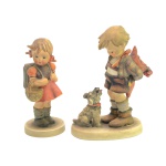 Par de estatuetas em porcelana alemã, policromada. representando crianças. Menino com cachorro (14 cm). Menina com cesta (13 cm).