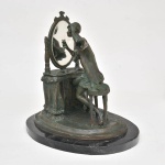 Escultura em Petit bronze, inspirada em Louis Icart, com base em granito, representando figura feminina sentada frente a penteadeira olhando-se no espelho. Med: 35 cm alt x 33 cm comp x 27 cm larg.