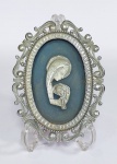 Lindo e antigo adorno religioso de mesa ou parede. Moldura em metal prateado, decorada com volutas e ao centro imagem de Nossa Senhora e o Menino Jesus em metal, sobre fundo de papelão. Medida: 15 cm x 11 cm x 1 cm. Obs: Não acompanha o suporte.