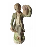 Escultório em porcelana policromada representando fidalgo carregando vaso e cesta de flores apoiado em tronco sobre base circular. Alt. 21, Diam. 7 cm.