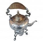 Antigo Samovar espessurado à prata lavrado e cinzelado em acantos, apoiado em pernas arrematada em pata de animal, alça recurva e com pega em madeira, o encaixe da trava está incompleto, Alt. 41, Diam. 20 cm.