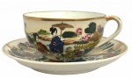 JAPÃO - Antiga xícara para chá e ou coleção em porcelana japonesa esmaltada fartamente adornada com motivo floral, paisagem e figuras humanas em policromia e vibrante ouro. Acompanha o seu respectivo pires com registro da manufatura.