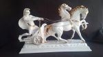 Belíssima biga conduzida por guerreiro romano em porcelana branca ricamente detalhado em ouro, mede 39cm x 58cm.