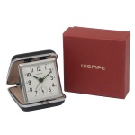 WEMPE - Relógio despertador alemão para viagem, de formato quadrangular, reclinável dentro de estojo servindo de base. Mostrador branco com ponteiras e numerais pretos. Acompanha caixa original. 7 x 7 cm / 6 x 6 cm / 4 x 8,5 cm.