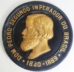 DOM PEDRO II IMPERADOR DO BRASIL  PLACA MEMORIAL  EM METAL PATINADO EM OURO E NEGRO COM EFIGIE DO IMPERADOR DOM PEDRO II E A LEGENDA: DOM PEDRO SEGUNDO IMPERADOR DO BRASIL (1840-1889). BRASIL, FINAL DO SEC. XIX OU INICIO DO XX. 39 CM DE DIAMETRO