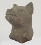 FRAGMENTO DE ESCULTURA VOTIVA COM FEITIO DE GATO. OFERENDA A BASTES, A DEUSA COM CABEÇA DE GATO QUE CONFERIA PROTEÇÃO, BOA SAÚDE E FERTILIDADE. CONSTRUIDA EM PASTA DE PEDRA (GRÃOS DE QUARTZO EM PÓ FINO FUNDIDOS COM PEQUENAS QUANTIDADES DE ÁLCALI E/OU CAL POR MEIO DE AQUECIMENTO PARCIAL) EPOCA SAÍTA, 700 AC. 10 CM ALTURANOTA: Bastet era provavelmente a mais conhecida das divindades felinas do Egito e era uma contraparte benevolente de Sekhmet, a deusa da destruição com cabeça de leão. Juntos, ilustram a natureza complexa dos gatos que os egípcios tanto admiravam: por um lado, podiam ser graciosos, vigilantes e férteis; por outro, podem ser agressivos, destrutivos e implacáveis.Embora as primeiras representações de Bastet a mostrem como uma leoa, mais tarde ela assumiu a forma de um gato doméstico ou de uma mulher com cabeça de gato. Amplamente popular em todo o Egito, o centro do seu culto era a cidade de Bubastis, ao norte do atual Cairo. Milhares de fiéis viajavam para lá todos os anos para um festival em sua homenagem, onde se bebia mais vinho do que em um ano inteiro, segundo o historiador grego Heródoto. Aqueles que buscavam o favor de Bastet deixavam oferendas votivas, como estatuetas ou múmias de gatos em vasos de madeira ou bronze, em seu templo. O arqueólogo suíço Édouard Naville descobriu milhares de gatos mumificados em Bubastis durante as suas escavações na década de 1880.