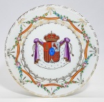 Antigo prato em porcelana europeia pintada a mão, decorado com brasão da nobreza, facha vermelha e amarela (cores da bandeira espanhola) cruzada com delicadas guirlandas florais e dourações. Sem marca. Med: 24,5 cm.