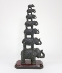 Escultura chinesa representando torre com os sete elefantes da sorte em material não identificado. Base de madeira. Med. 36 cm