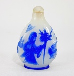 CHINA, DINASTIA QING - SÉC.XIX /XX - Antigo snuff bottle em 'Peking Glass' (Vidro de Pequim) branco e azul, decorado com relevo de Imortal e flores. Tampa em pedra. Paleta em Marfim. Med. 7 x 5 cm.