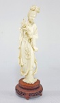 CHINA, Circa de 1900 - Antiga escultura chinesa em Marfim delicadamente esculpida representando Cortesã com Lírio. Movimento suave e detalhes minuciosos. Base em madeira. Medida total 28 cm. Possui discreto fio na lateral.