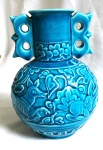 Graciosa e bojuda floreira oriental em porcelana vitrificada no tom azul ao gosto Celadon decorada por 2 alças estilosas. Mede 20cm