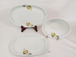 Renner - Três travessas em porcelana branca Renner com decoração floral amarela, bordas em filete de outro, sendo duas travessas ovais e uma travessa funda. Med: 29 x 19 cm; 33 x 22 cm; 22 diametro.