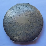 METAL - Antigo estojo para maquiagem em metal branco espessurado a prata, ricamente lavrado com motivos vegealistas. Espelho interno trincado. Dia. 7 cm.